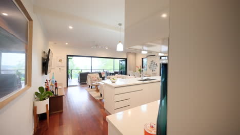 Wide-angle-overview-of-open-plan-kitchen-with-modern-stainless-steel-appliances-and-doors-out-to-balcony-patio