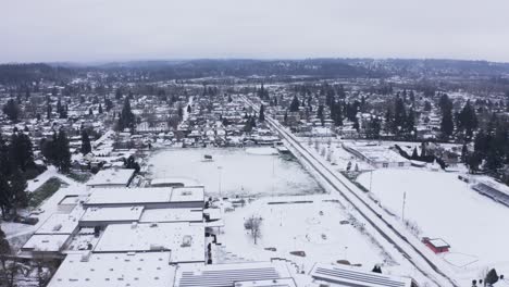 Toma-Aérea-Sobre-La-Escuela-Secundaria-De-Una-Pequeña-Ciudad-En-Un-Día-Nevado-Con-El-Río-Al-Fondo