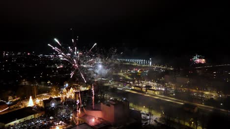 Feuerwerk-In-Einer-Kleinen-Stadt,-Das-In-Verschiedenen-Farben-Explodiert,-Darunter-Rot,-Grün,-Blau,-Gelb-Und-Orange,-Vor-Einem-Dunklen-Nachthimmel