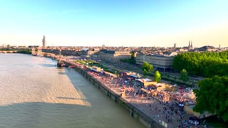 Crowded-shore-of-the-Garonne-river-during-Wine-Fair-near-Galleon-ship,-Aerial-orbit-shot