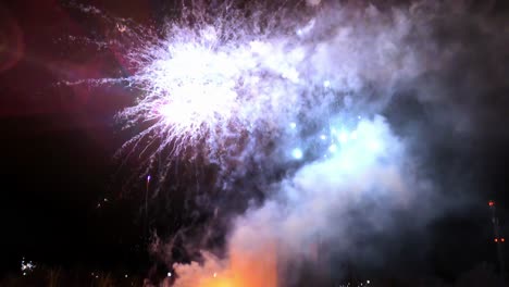 Colorful-fireworks-display-illuminating-the-night-sky-behind-a-dark,-monolithic-building