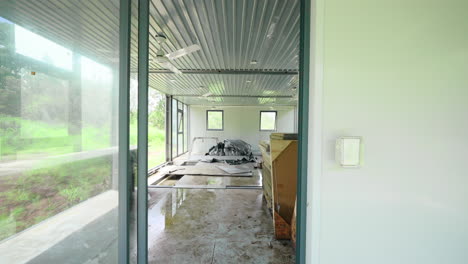 Dolly-to-door-entrance-into-open-space-half-constructed-demountable-container-home-with-wood-supplies-and-bare-corrugated-metal-roof