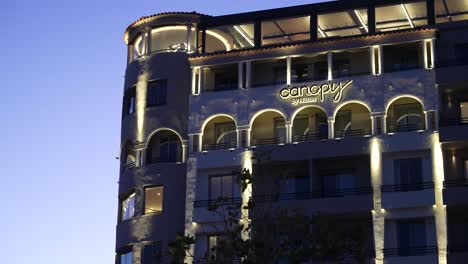 Hotel-Canopy-De-Hilton-Iluminado-Por-La-Noche-Con-Cielo-Despejado,-Toma-Larga-Con-Cámara-En-Mano