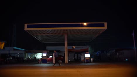 Shot-of-gas-station-at-night-with-car,-bike-and-runner