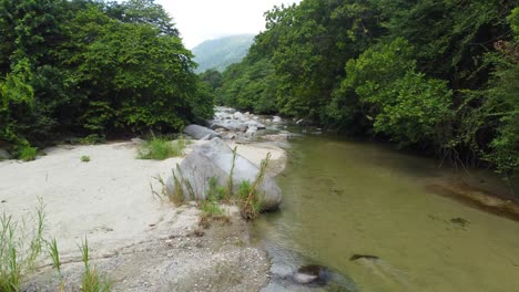 Aerial-lush-vegetation-fly-over-rocky-creek-in-Santa-Marta-Colombia