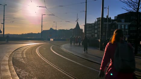 Amsterdamer-Innenstadt-Im-Gegenlicht-Mit-Fußgängern-Und-Straßenbahnschienen