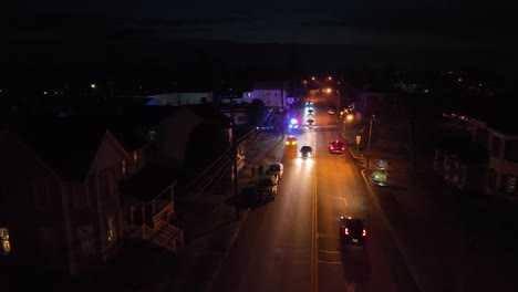 Nighttime-aerial-view-of-a-street-with-police-lights-reflecting-on-the-road