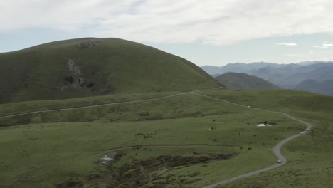 Coches-Antiguos-Conduciendo-Por-Caminos-Rurales-Con-Caballos-Salvajes-Pastando-En-Campos-Verdes-De-Col-Inharpu,-Pirineo-Vasco,-Francia