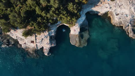 A-down-wards-pulling-out-drone-shot-of-tourists-enjoying-themselves--Galebijana-Cave-Pula