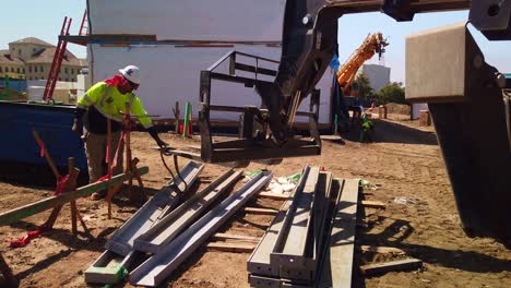 Gimbal-panning-shot-of-an-industrial-fork-lift-carrying-a-pre-fabricated-steel-beam-at-a-modular-construction-site-in-West-Los-Angeles,-California