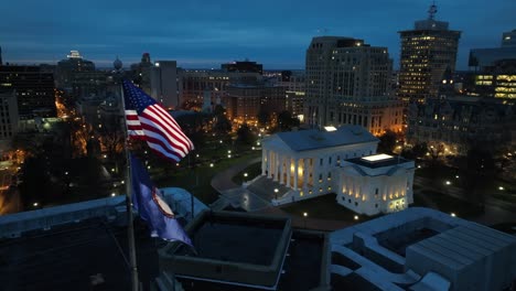 American-and-Virginia-flags-waving-in-downtown-Richmond-in-front-of-lit-state-capitol-building-at-night
