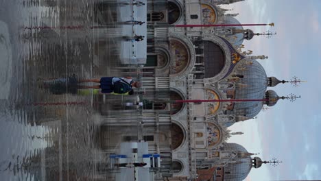 Frau-Geht-Während-Aqua-Alta-Auf-Sohn-Zu,-Um-Fotos-Auf-Dem-Markusplatz-In-Venedig-Aufzunehmen