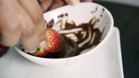 Close-up-of-dipping-strawberries-in-melted-chocolate-to-make-chocolate-covered-strawberries-valentines-day-beet-muffin-vegan-recipe