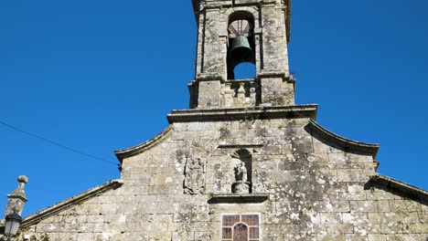 Pan-down-across-old-stone-bell-tower-and-weathered-rocks-of-San-Xoan-de-Rio-church