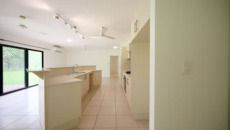 Vacant-Large-Modern-Beige-Kitchen-And-Clear-Counters-to-Large-Empty-Bedroom-With-Sliding-Mirrored-Cabinet-Doors