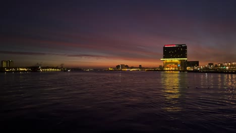 Noche-Crepuscular-Exterior-Del-Hotel-Movenpick-Junto-Al-Río-Ij-En-Amsterdam,-Países-Bajos