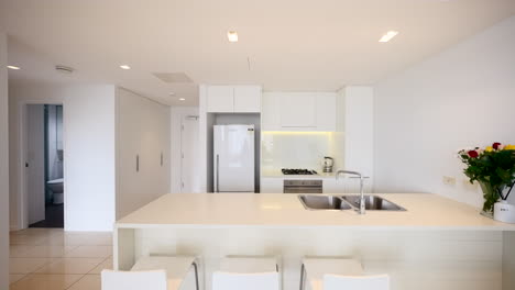 Small-Modern-Clean-White-Tiled-Apartment-Interior-Kitchen-With-Bar-Seating-And-Floral-Flower-Bouquet