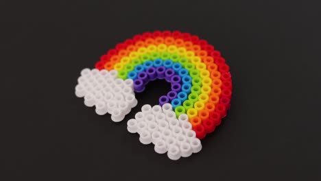 Colorful-plastic-bead-rainbow-on-black-background,-vibrant-craft-project