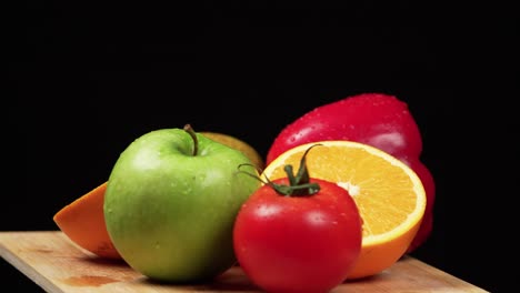 Frutas-Y-Verduras-Coloridas-Girando-Sobre-Una-Tabla-De-Madera-Sobre-Un-Fondo-Negro