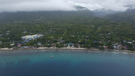 Oslob-coastal-town-with-clouds-over-mountains,-cebu-island,-philippines,-daylight,-aerial-view