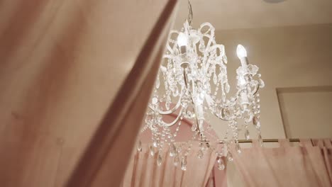 A-Cozy-Bedroom-with-a-Crystal-Chandelier-Suspended-Overhead---Low-Angle-Shot