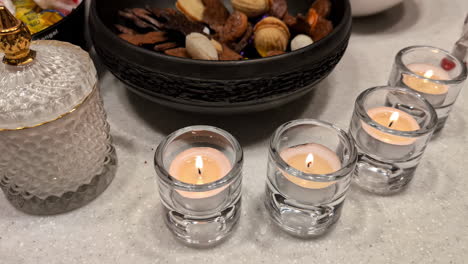 Nahaufnahme-Eines-Glases-Mit-Flackernden-Kerzen,-Die-In-Einem-Glas-Auf-Einem-Tisch-Brennen