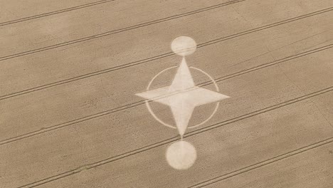 Arcing-aerial-view-of-star-like-crop-circle-in-farm-land,-Preston-Candover