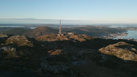 Sunset-hues-over-Ulriken,-Bergen-with-a-radio-tower-dominating-the-landscape,-shadows-stretch-long