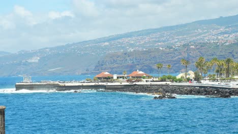 Stable-shot,-promenade-Puerto-de-la-Cruz,-sunny-Tenerife,-waves-hitting-shore-slow-mo