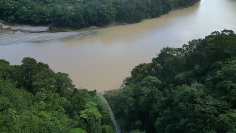 Drone-Volando-Sobre-Un-Frondoso-Bosque-Con-Un-Río-Al-Fondo,-Muchas-Aguas-En-San-Cristobal-En-República-Dominicana