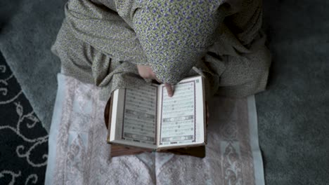 Overhead-view-of-person-reading-Quran-on-a-rug,-intimate-and-spiritual-atmosphere,-close-up