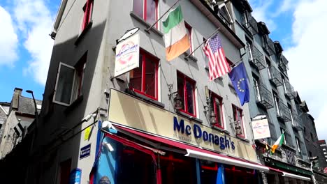 Flags-flutter-above-McDonagh's-restaurant-on-a-sunny-day-in-Galway,-Ireland