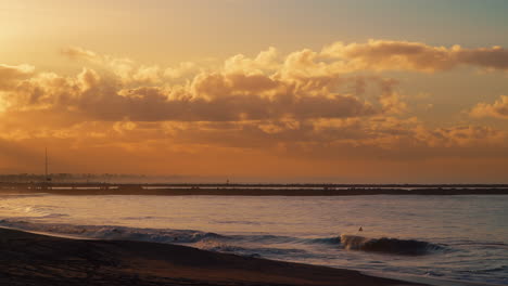 Goldener-Sonnenaufgang-über-Seal-Beach-Mit-Ruhigen-Wellen-Und-Klarem-Horizont,-Der-Warme-Farben-Auf-Dem-Wasser-Reflektiert,-Weitwinkelaufnahme