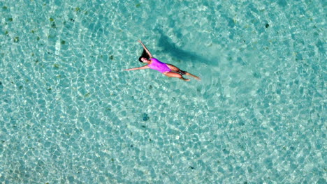 Eine-Frau-In-Einem-Rosa-Badekleid-Schwimmt-Im-Transparenten-Mittelmeer,-Von-Oben-Betrachtet