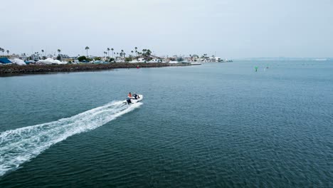 An-electric-jet-sky-boat-sails-through-coastline-waters-of-Californian-oceanside-American-travel-beach-destination-aerial-drone-view