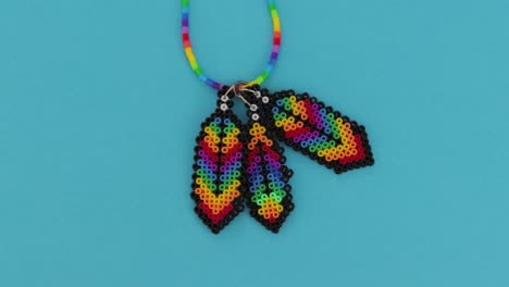 Colorful-bead-necklace-in-vivid-hues-on-sky-blue-background,-showcasing-craft-and-design