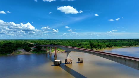 Stunning-drone-video-of-the-Paraguay-River-and-bridge,-showcasing-the-vast-Pantanal-wetlands-under-a-clear-blue-sky