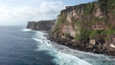 Drone-view-of-spectacular-cliffs,-coastline-and-waves-in-Uluwatu,-Bali,-Indonesia