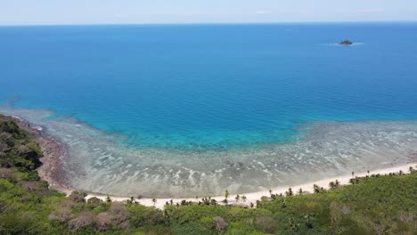 Vista-Aérea-De-Una-Isla-De-Fiji-Caracterizada-Por-Playas-De-Arena-Blanca,-Rodeadas-De-Aguas-Claras-Y-Poco-Profundas-Que-Pasan-A-Tonos-Azules-Más-Profundos-A-Medida-Que-Se-Alejan-De-La-Costa.