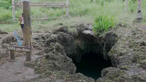 Person-leaps-into-the-clear-waters-of-Cabagnow-Pool-Cave-in-the-Philippines,-surrounded-by-lush-greenery