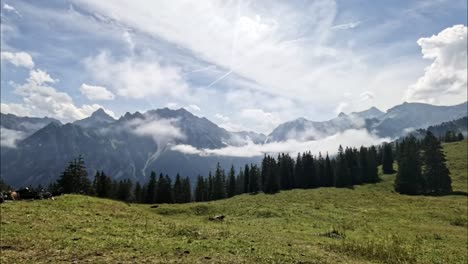 Timelapse-De-Nubes-Volando-Sobre-El-Pintoresco-Paisaje-Montañoso-En-Los-Alpes-Austriacos-De-Europa-Con-Vacas-Caminando-Y-Comiendo-Hierba