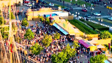 Large-crowds-gather-at-Wine-Fair-near-massive-sailing-ships-in-the-afternoon,-Aerial-approach-shot