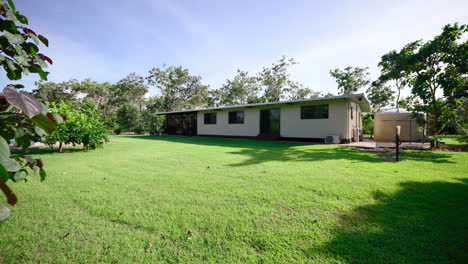 Rural-Large-Property-Small-Rectangular-House-With-Large-Backyard-on-Sunny-Day,-Dolly-Reveal-Past-Foliage