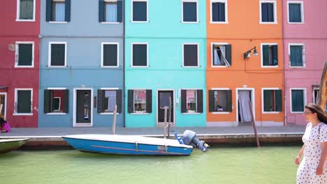 Female-tourist-walks-and-poses-in-front-of-Burano-canal-and-colorful-houses