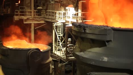 Molten-metal-being-poured-in-foundry,-intense-orange-glow,-industrial-setting,-heat-and-smelting-process,-night-shot