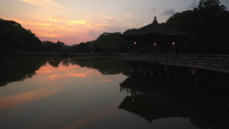 During-sunset,-behold-the-captivating-Toda-ji-temple-compound,-where-vibrant-orange-hues-reflect-on-the-water,-accentuating-the-charm-of-the-small-temple-in-Nara,-Japan