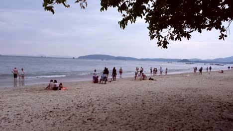 Tourists-and-locals-converge-on-Aonang-Beach,-Krabi,-Thailand,-enjoying-the-sun,-sand,-and-vibrant-atmosphere-of-the-turquoise-waters-before-sunset-arrives