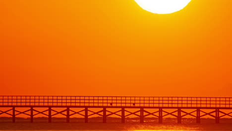 Moonrise-Against-Red-Warm-Sky-Over-A-Wooden-Bridge