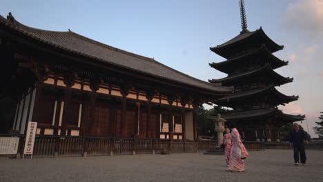 A-charming-view-showcases-Toda-ji-tower-with-Asian-tourists-adorned-in-traditional-Japanese-attire-nearby,-framed-by-the-Bell-tower-in-Nara,-Japan
