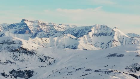 Silhouette-of-a-snowy-mountain-range-seen-from-above-at-dawn-via-drone